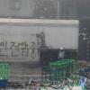 -2009년 8월 4일 뿌연 연기속에서 쌍용차 노동자들이 살인진압중단이라고 새겨진 컨테이너 앞에 모여있다