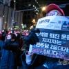 -11월 26일 오후 서울 세종대로에서 열린 윤석열 퇴진 집회에서 한 참가자가 <노동자 연대> 신문을 팻말로 활용하고 있다.