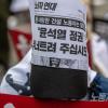 -5월 6일 오후 서울 세종대로에서 열린 윤석열 퇴진 집회에서 한 참가자가 고 양회동 열사의 유언이 적힌 <노동자 연대> 리플릿을 머리에 쓰고 있다.